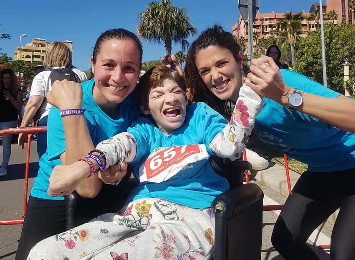 Usuaria de AMAPPACE en silla de ruedas junto a dos acompañantes durante una carrera solidaria